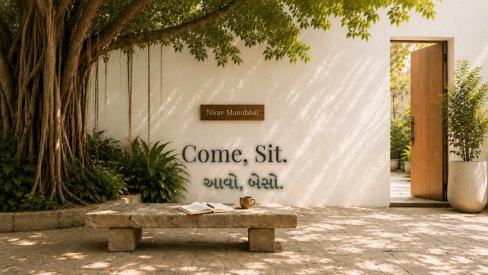 The courtyard: a banyan tree, a stone bench, an open door — Come, Sit. આવો, બેસો.